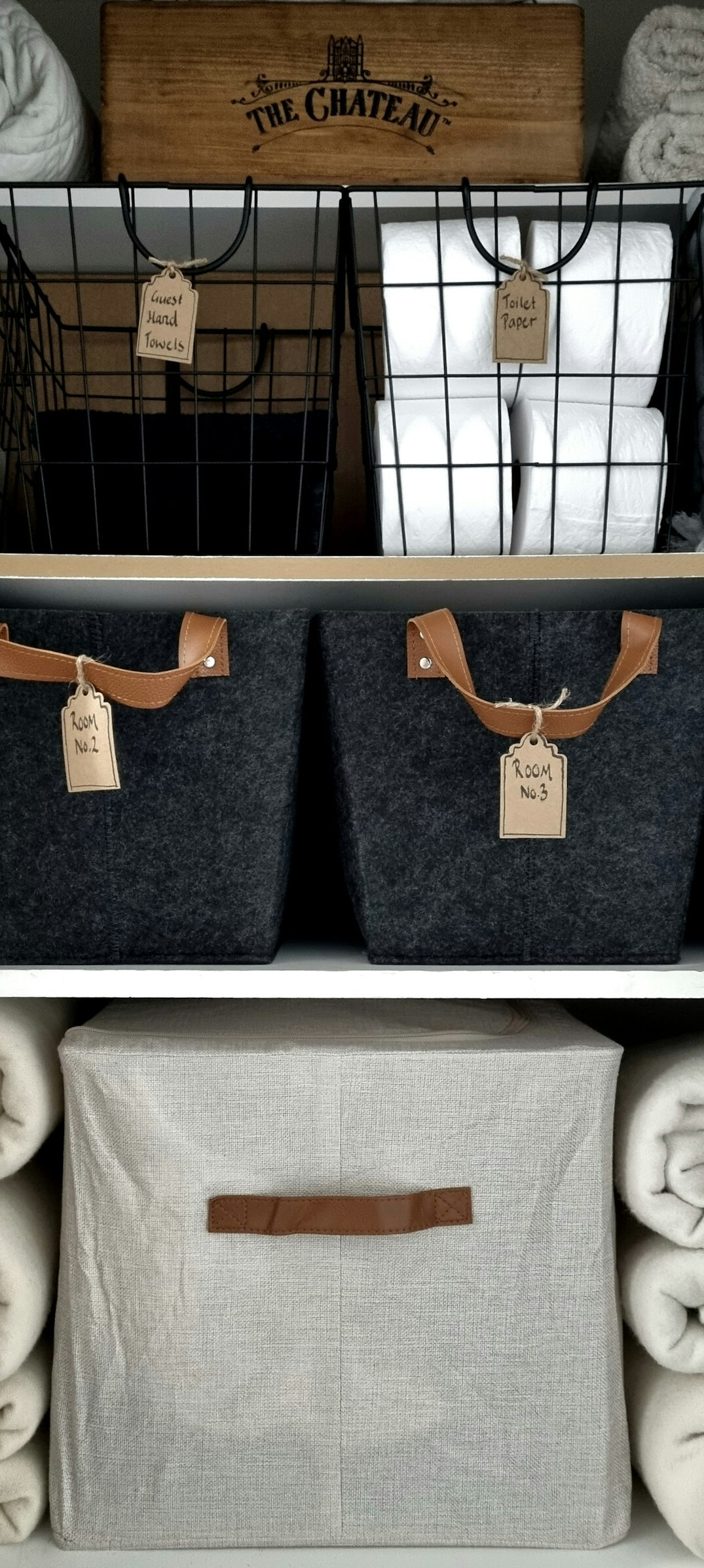 Tidy wooden shelf with labeled storage baskets and folded linens in a bright home