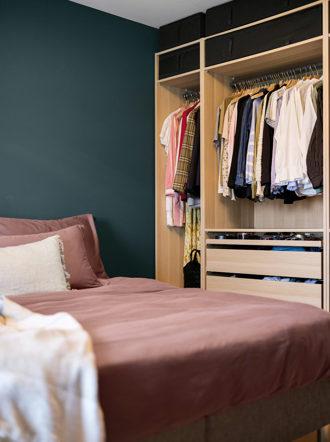 Open wardrobe with neatly folded clothes sorted by color and hanging shirts