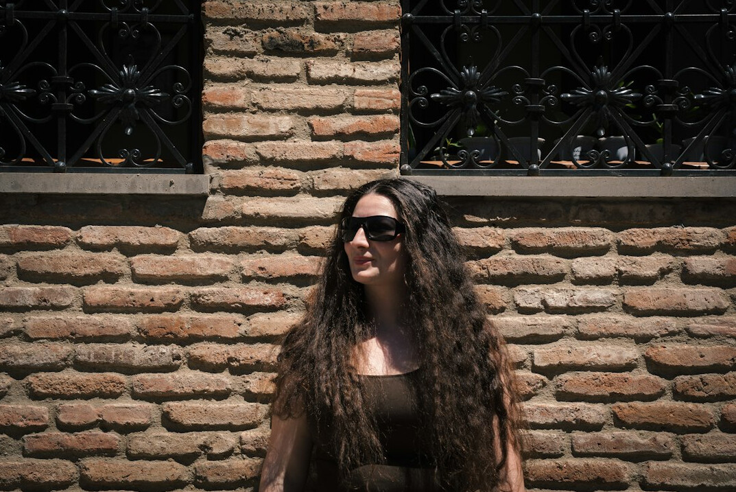 Portrait of a young woman with long dark curly hair smiling at the camera