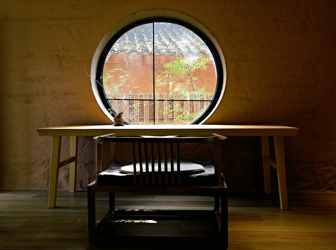 Wooden desk with laptop, notebook and pen near a window